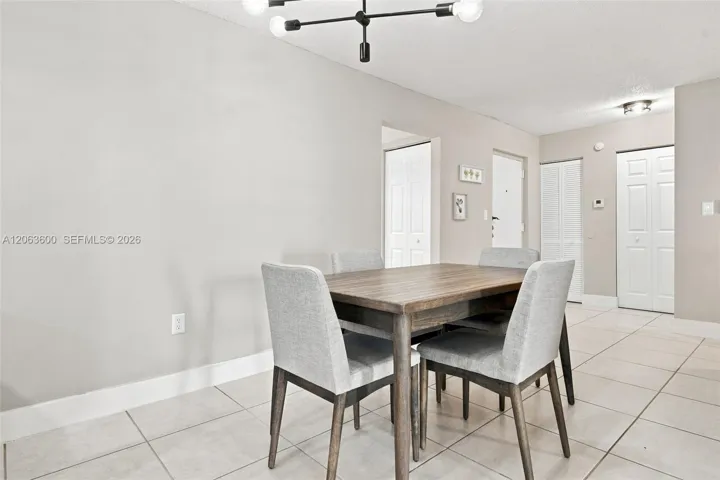 Dining space with pendant lighting fixture, tile flooring, and view toward the entry foyer and closets.