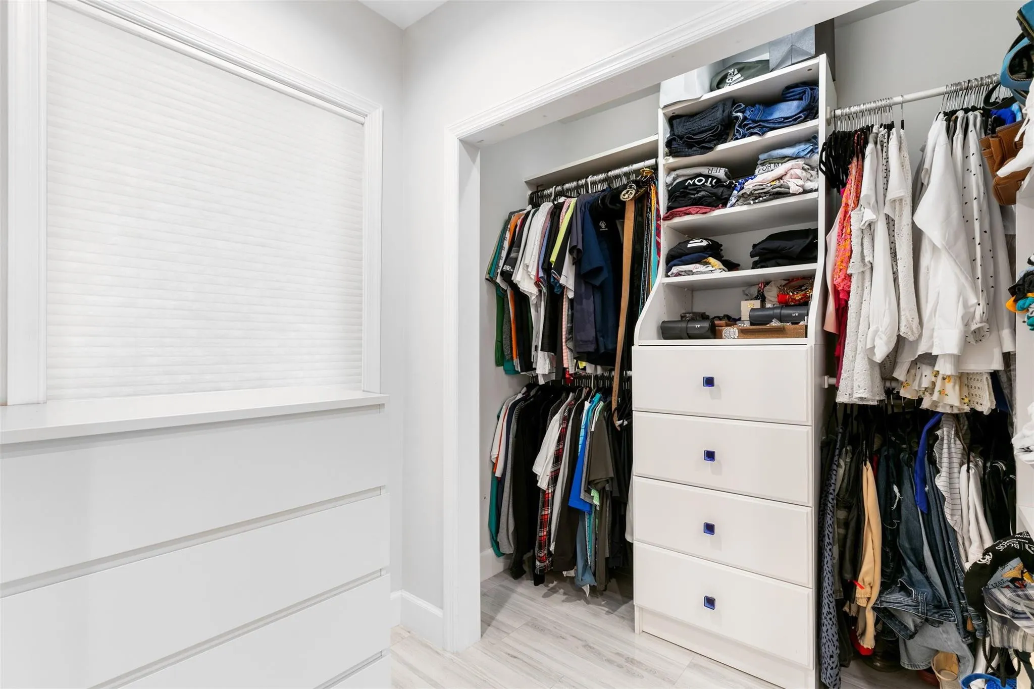 Custom closet system featuring shelving, hanging rods, and built-in drawers with blue hardware