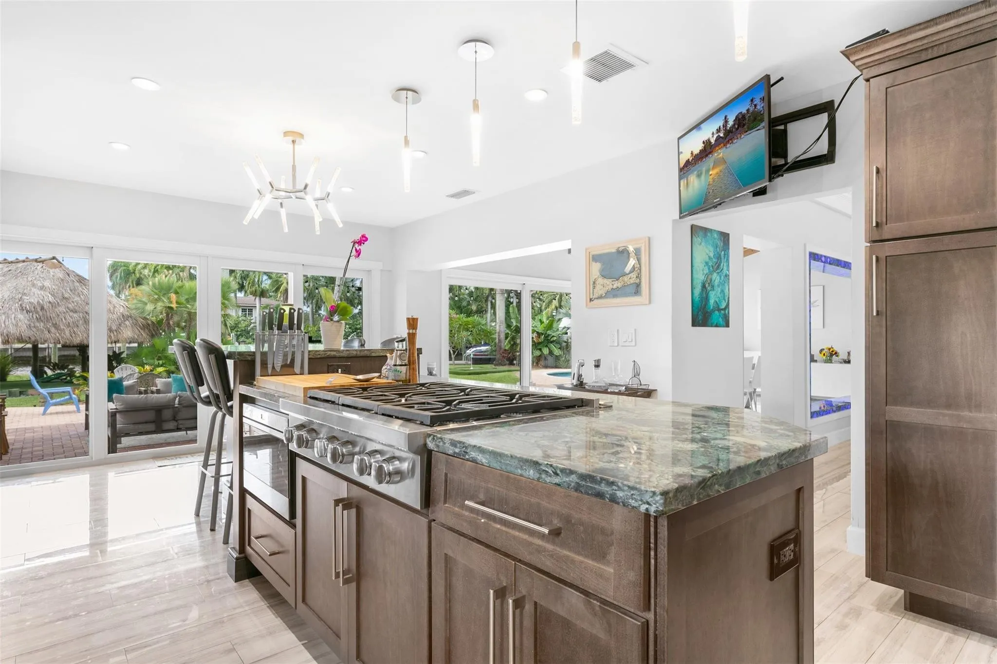 Gourmet kitchen with a large central island featuring a built-in range, stainless steel appliances, and a polished stone countertop