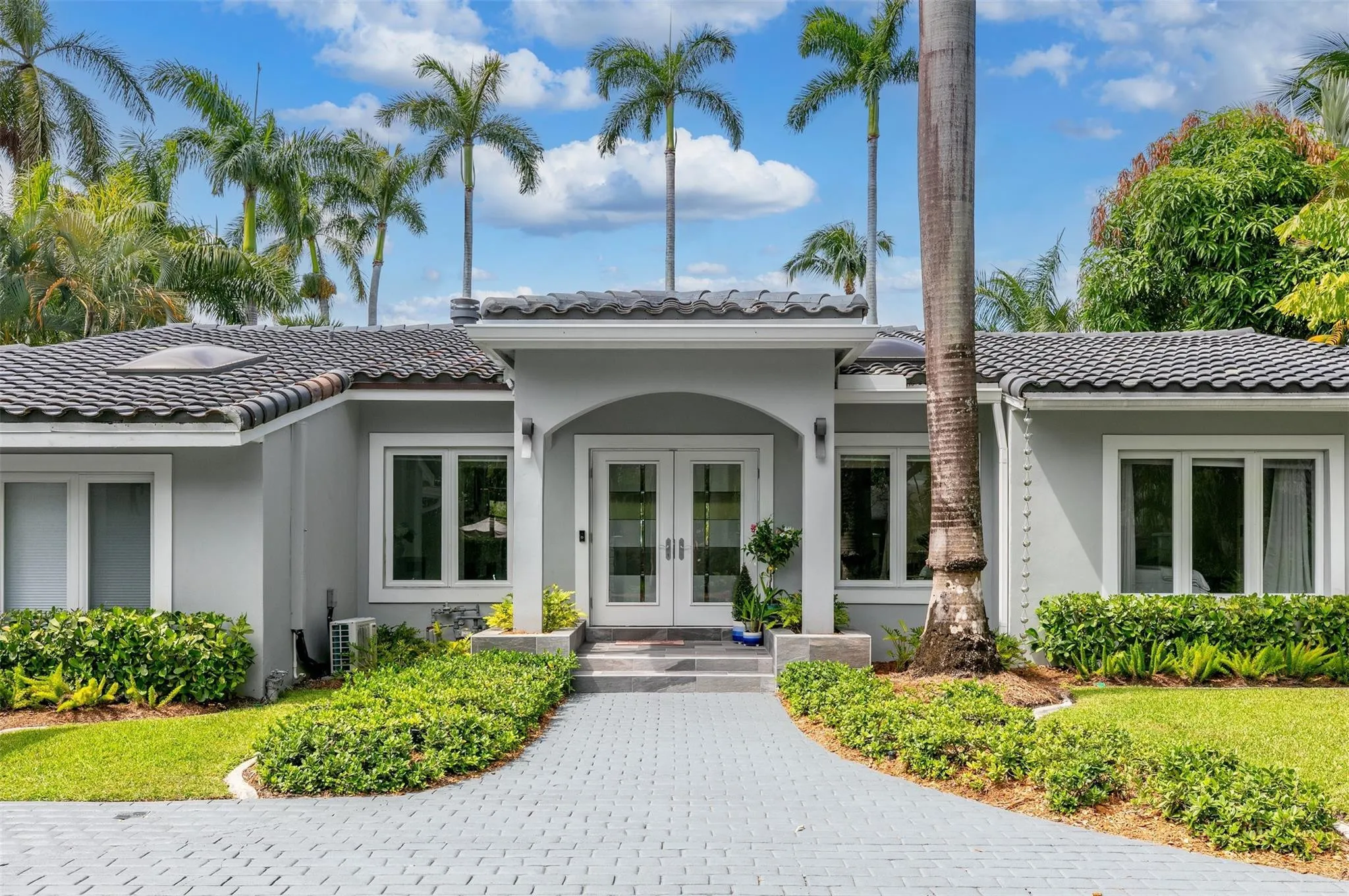 Exterior featuring a tiled roof, light gray stucco facade, and white-framed windows