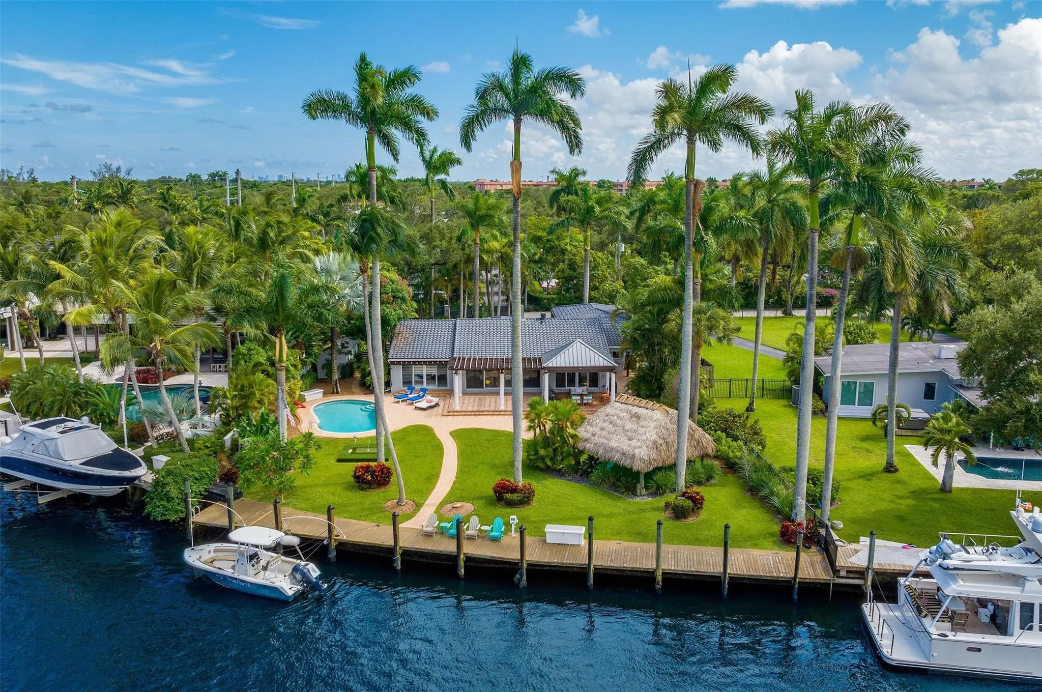 Waterfront property featuring a private dock, inground pool, and mature palm trees