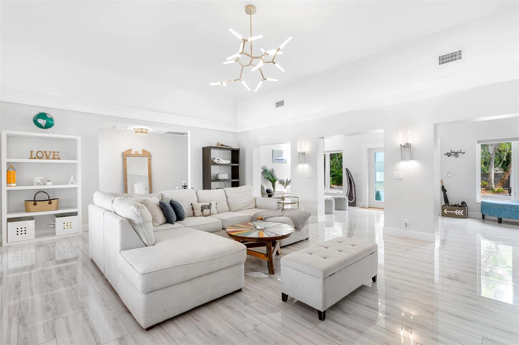 Spacious open-concept room featuring high ceilings, white wood-finish flooring, and multiple windows providing natural light