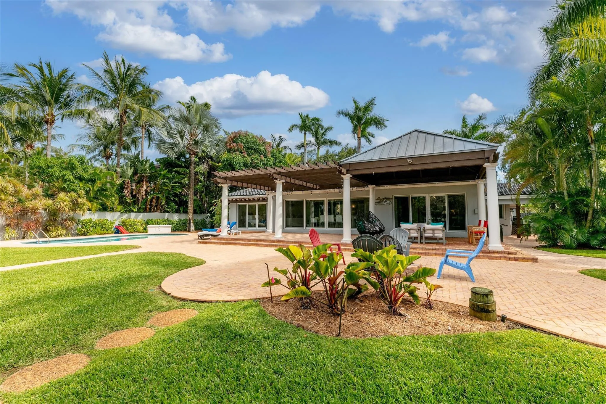 Expansive outdoor living area featuring a large brick paver patio, a covered patio with a metal roof, and a wood pergola