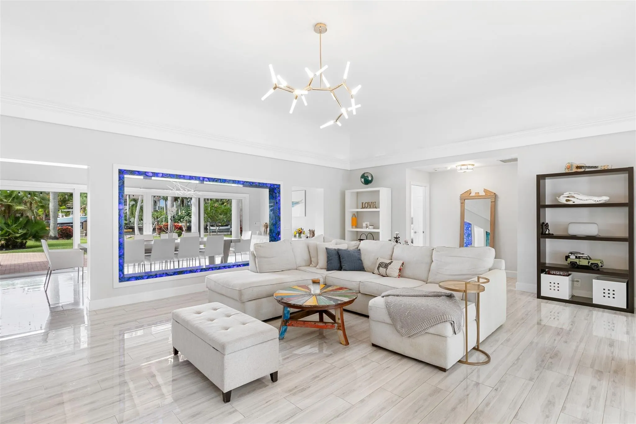 Spacious living area featuring polished tile flooring, a vaulted ceiling, and a contemporary chandelier