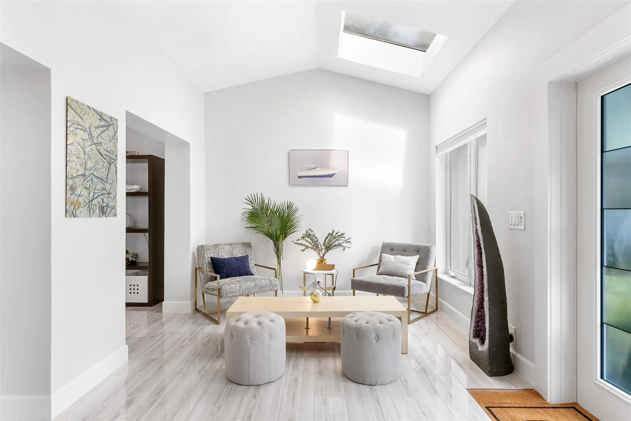 Bright living space featuring a vaulted ceiling with skylight, recessed lighting, and wood-finish flooring