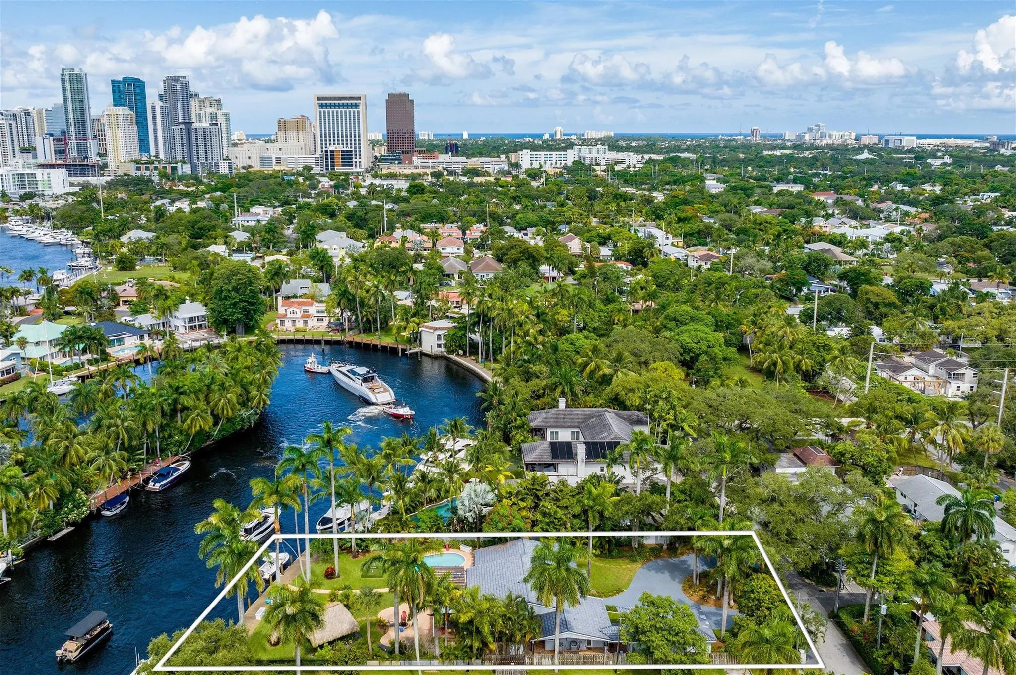 Waterfront property featuring a private boat dock, lush tropical landscaping, an outdoor pool, and a thatched-roof structure