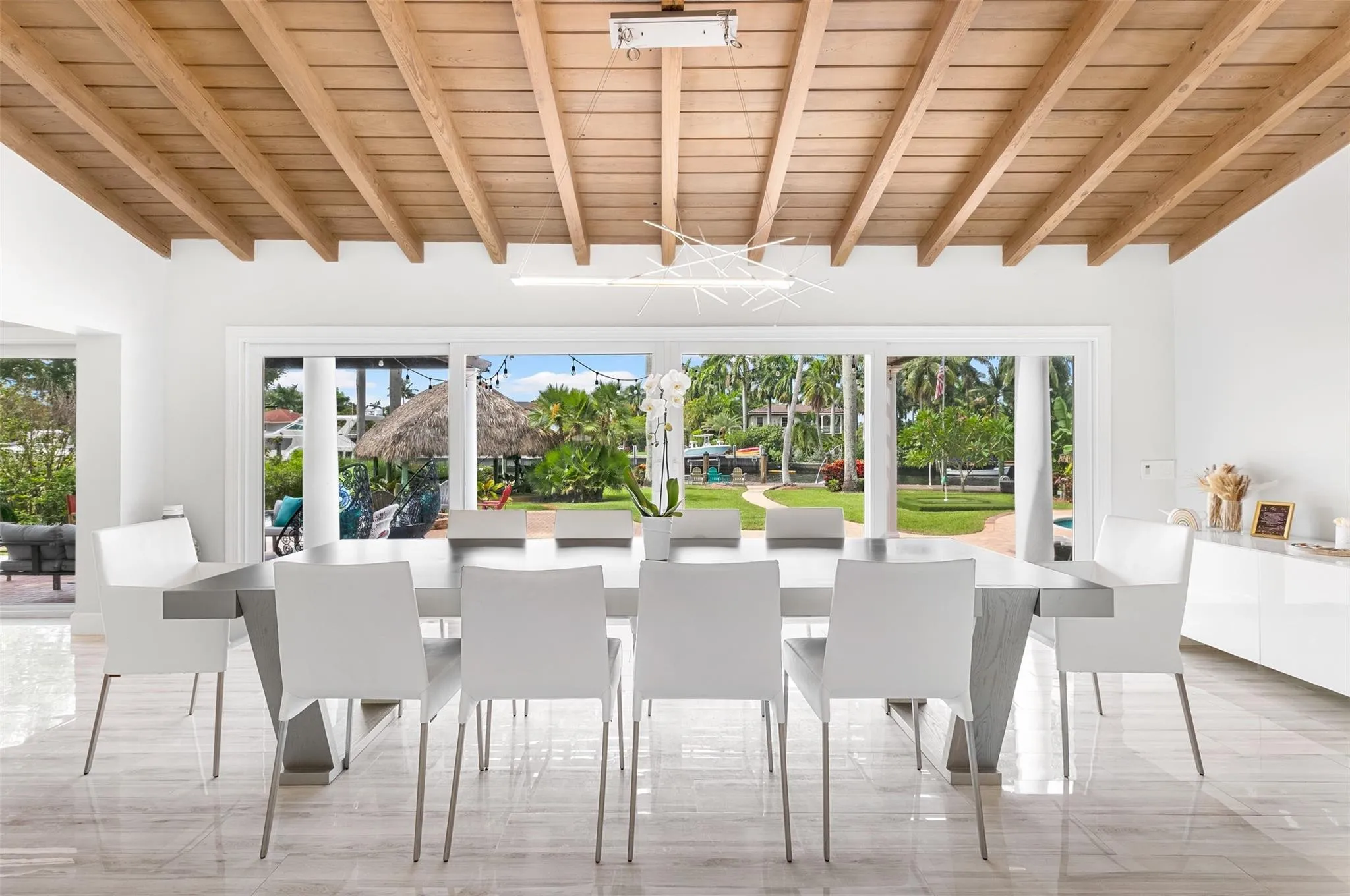 Spacious dining area featuring a wood-beam ceiling, white walls, and light-toned tile flooring