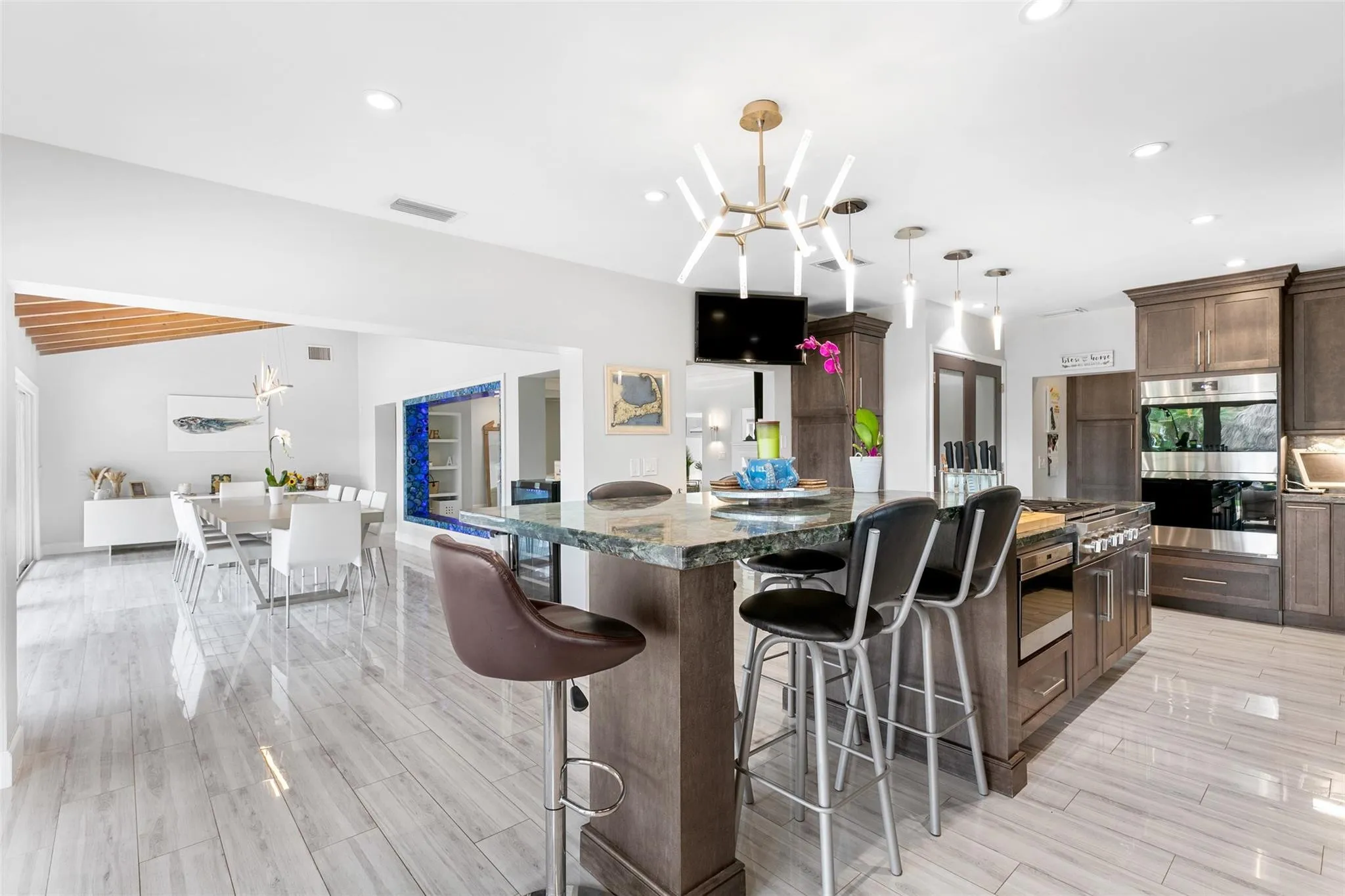 Gourmet kitchen featuring a large island with seating, stainless steel appliances, dark wood-finish cabinetry, and recessed lighting