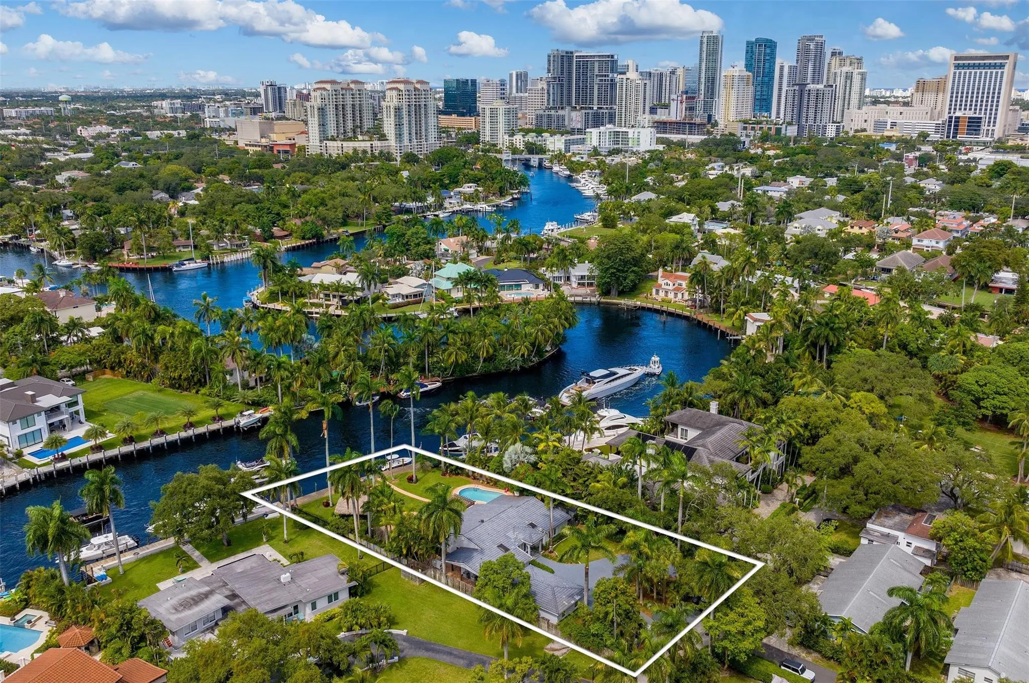 Canal-front property with a private pool, lush tropical landscaping, and mature palm trees