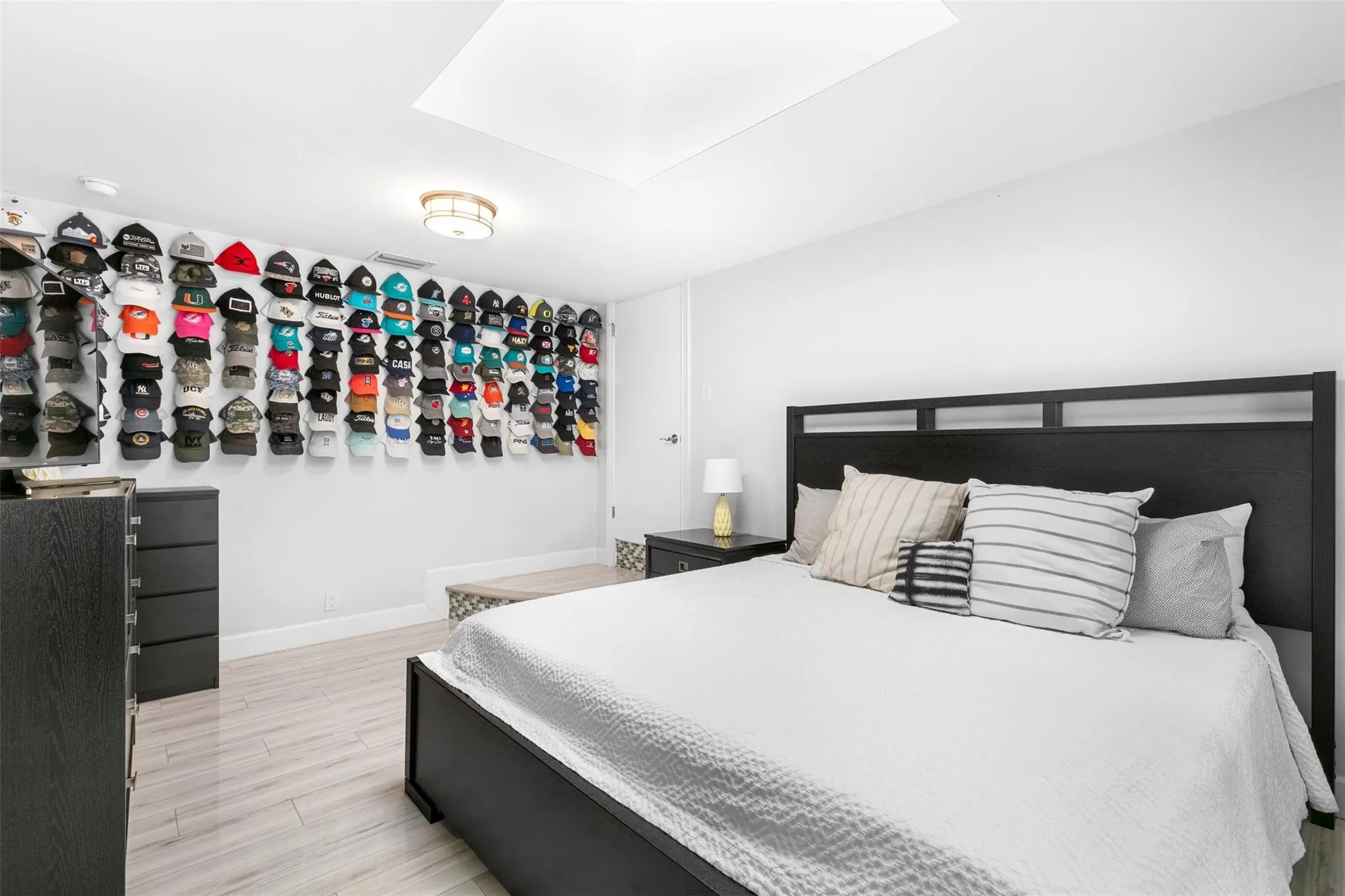 Spacious room featuring light wood-finish flooring, recessed ceiling lighting, and a skylight