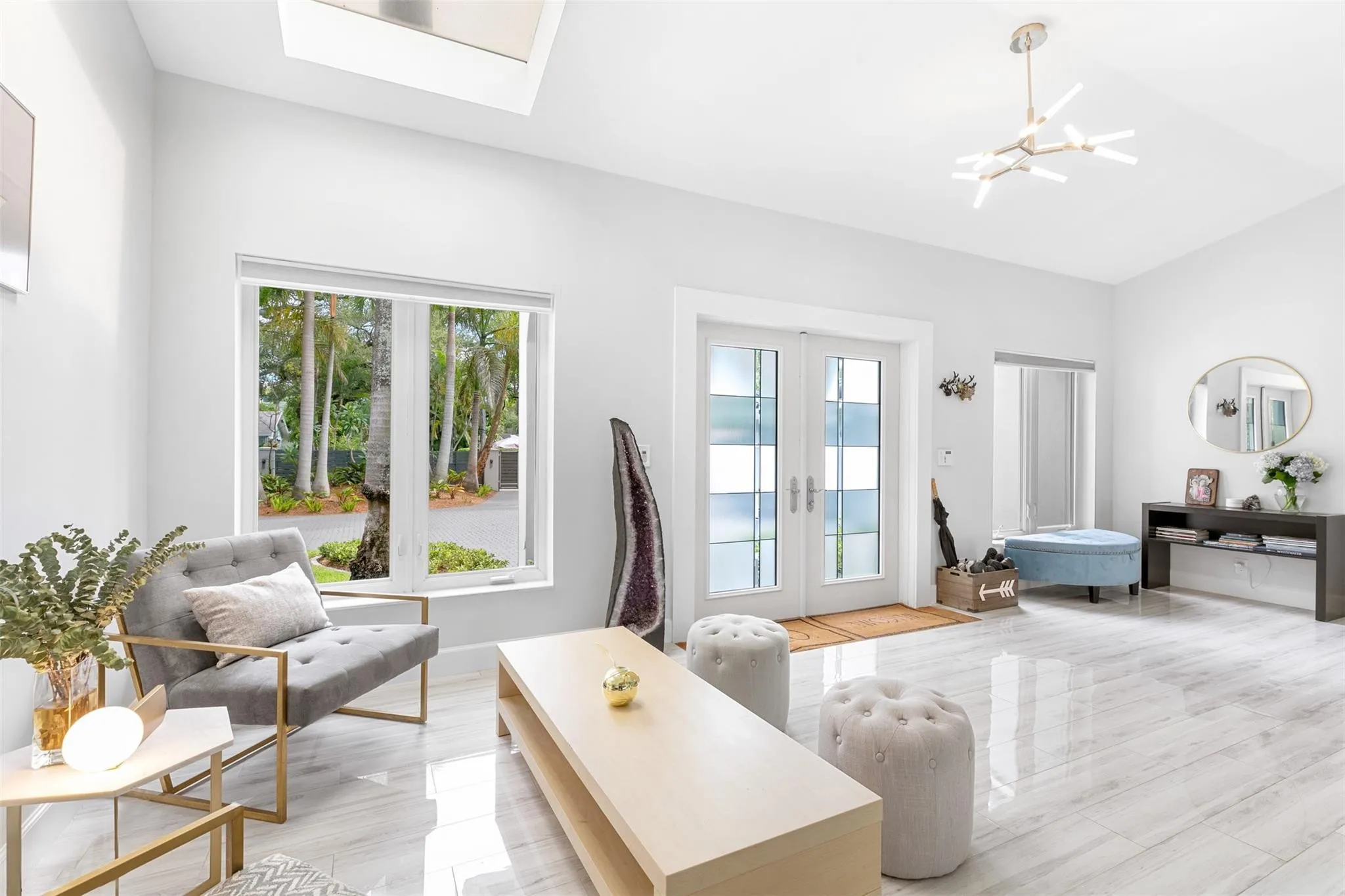 Spacious living area featuring polished tile flooring, white walls, and a skylight