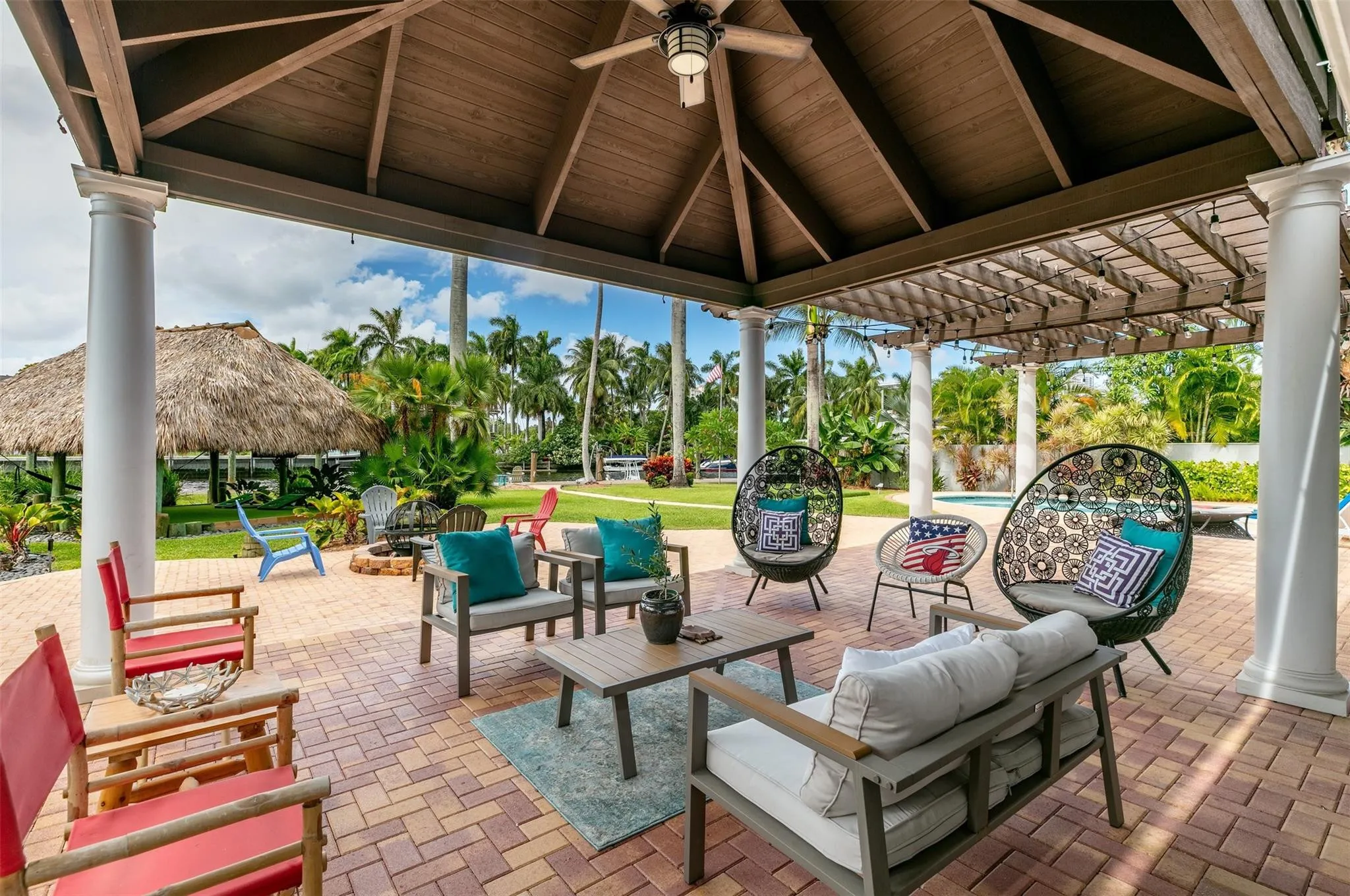 Expansive covered patio featuring a vaulted wood-finish ceiling, ceiling fan, and decorative pergola