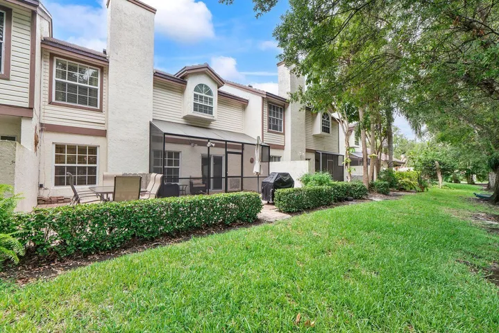 Expansive grassy area bordering a private screened patio, ideal for outdoor living