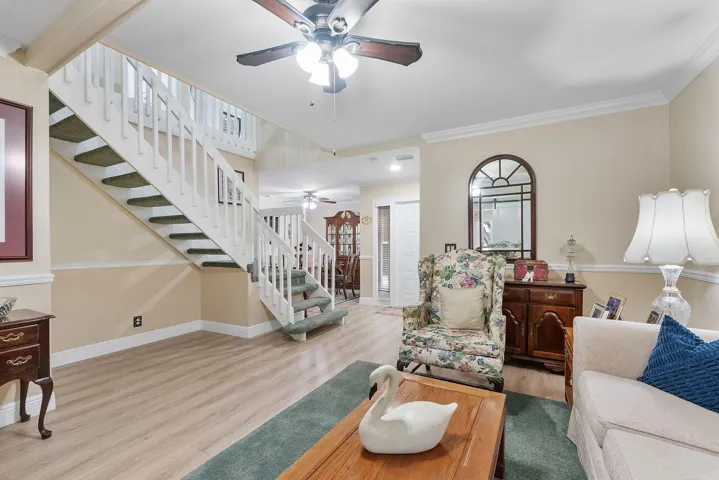 Living area featuring upgraded flooring, a white staircase with carpeted treads leading to upstairs bedrooms and loft