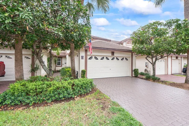 Exterior featuring a tiled roof, light-toned stucco finish, and a paver driveway