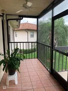 Screened balcony featuring terracotta-toned tile flooring, black metal railings, and a ceiling fan