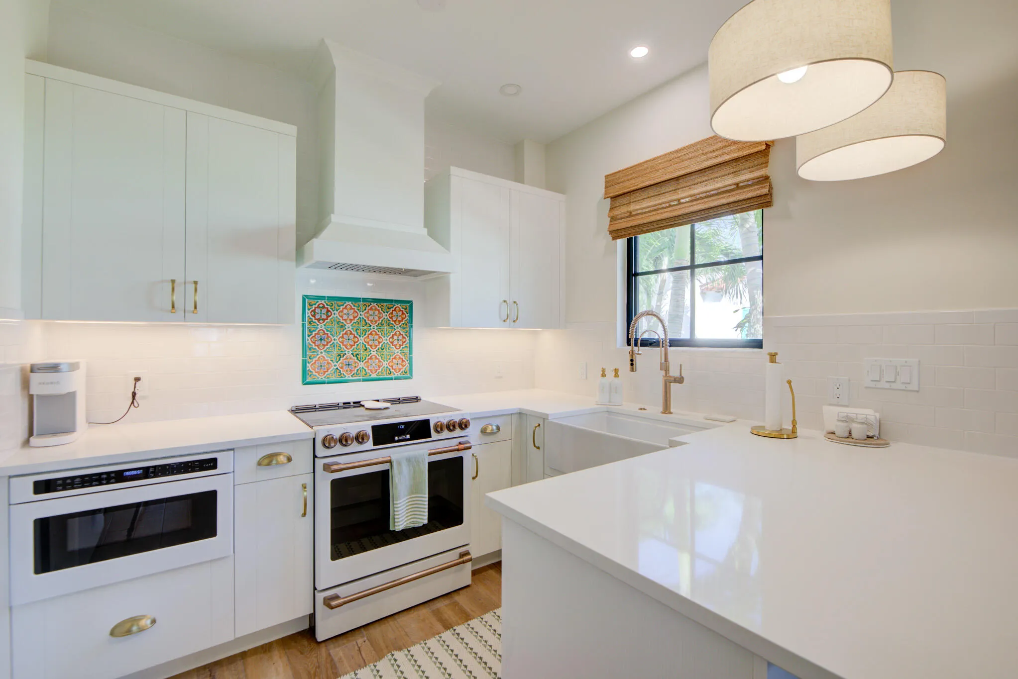 White kitchen featuring a farmhouse sink, stainless steel appliances, white cabinetry, integrated drawer microwave, and wood-finish flooring