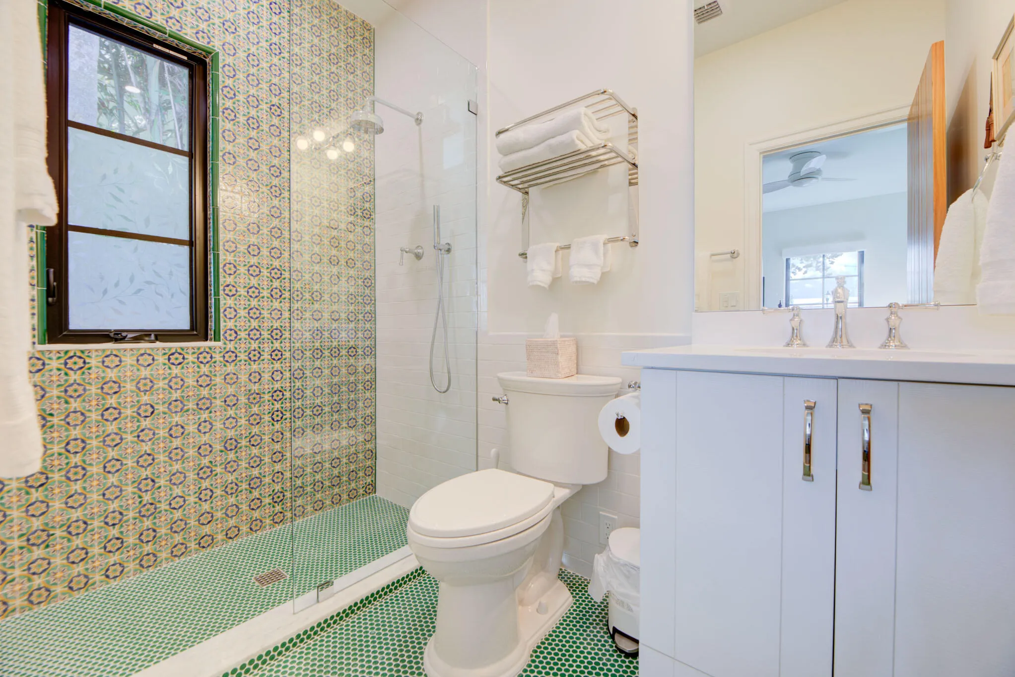 Bathroom featuring a walk-in shower with patterned tile surround and green mosaic floor
