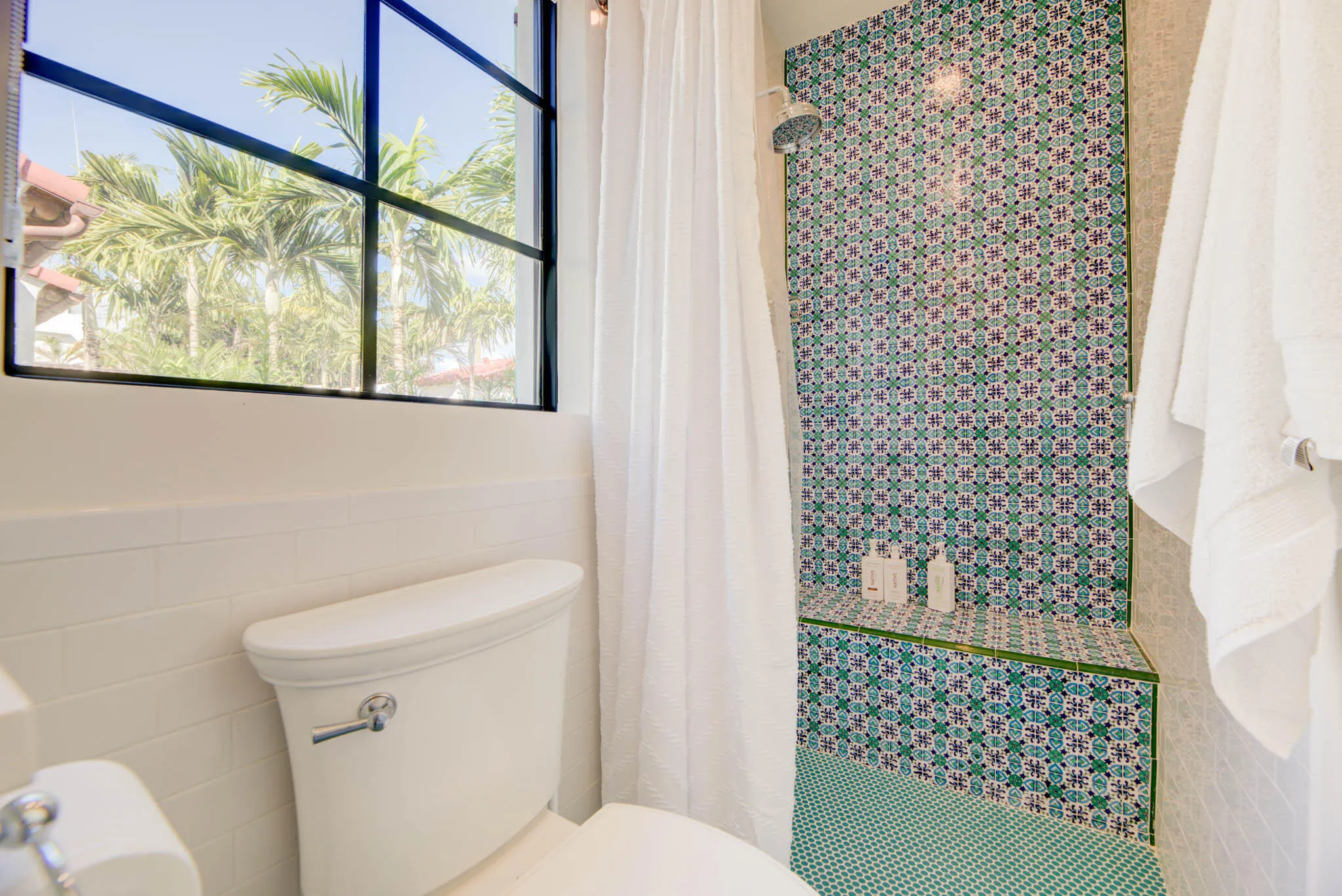 Shower with vibrant patterned tile work, an integrated bench, and a rainfall showerhead