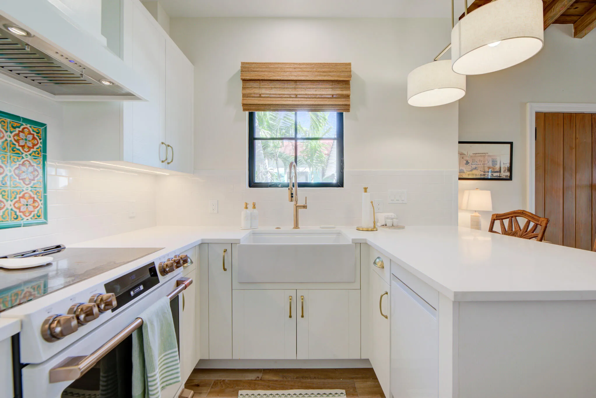Modern kitchen featuring white cabinetry, a white apron-front sink, white quartz countertops, wood-finish flooring, and pendant lighting
