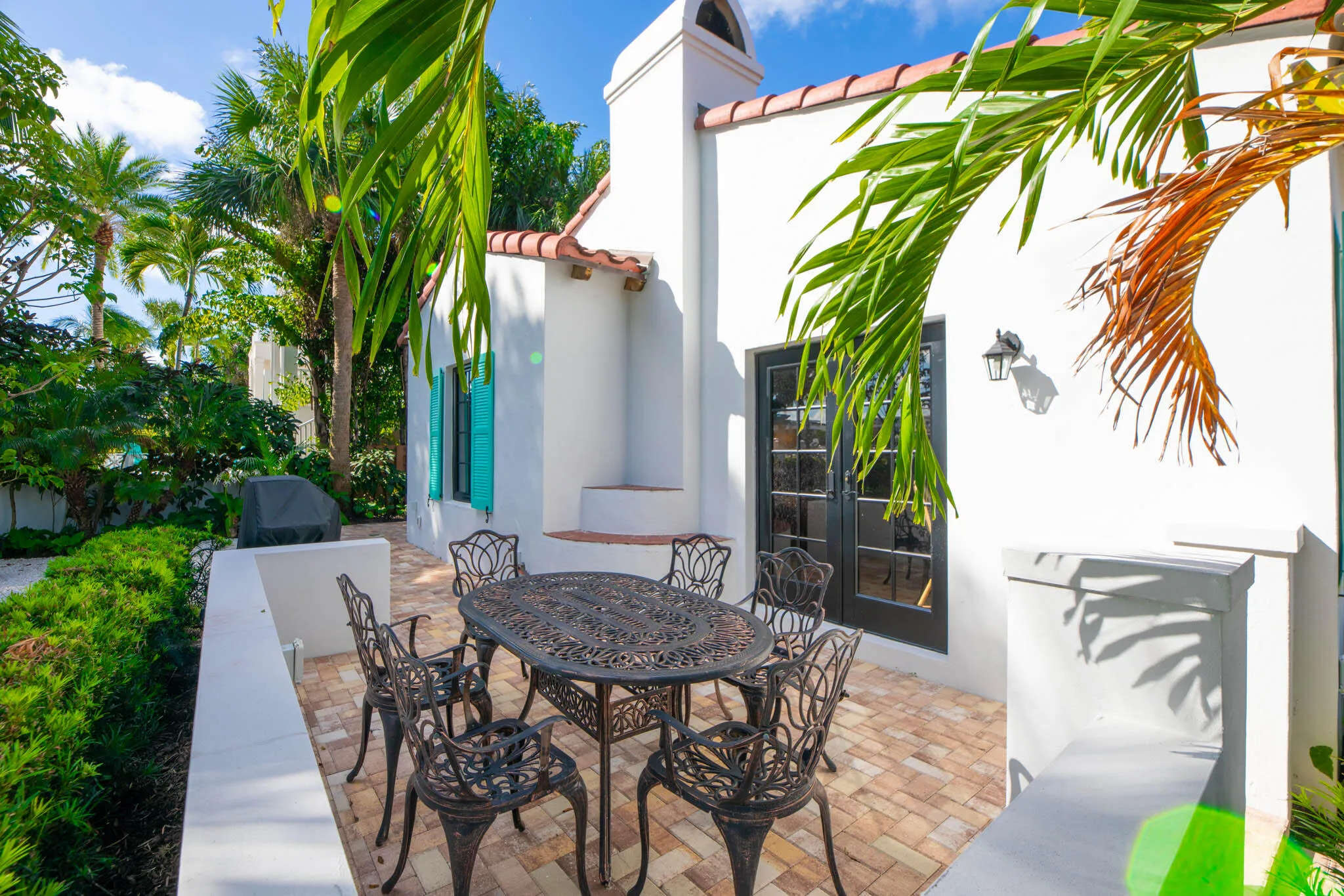 Private outdoor patio featuring brick pavers and a white stucco wall