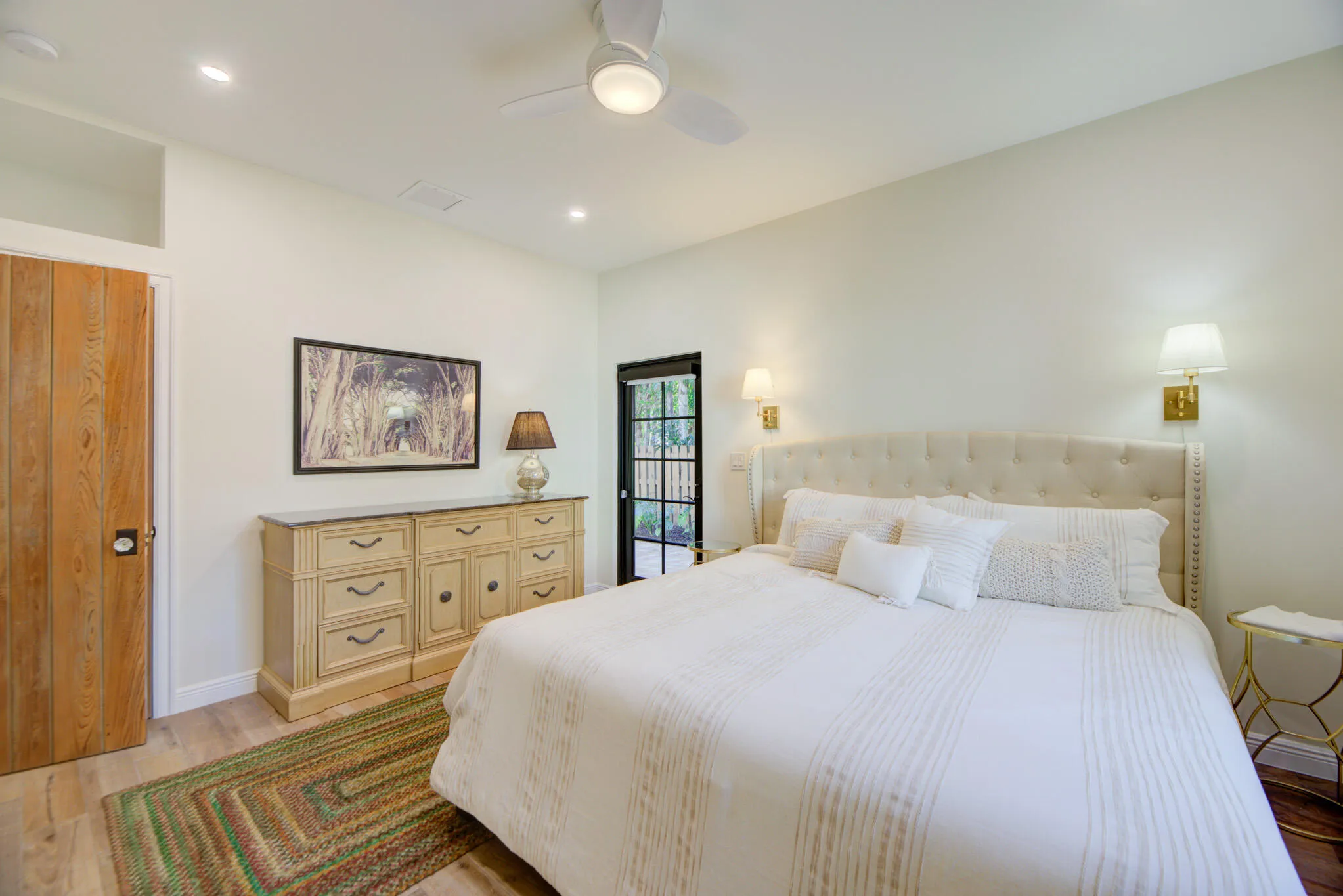 Bright bedroom featuring a panel door with dark hardware, recessed lighting, and a ceiling fan with integrated lighting