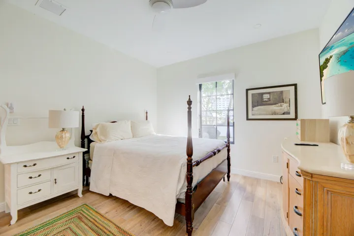 Light wood-finish flooring complements the neutral wall color in this space, featuring a window with dark framing and a ceiling fan