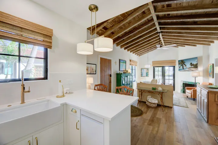 Kitchen island featuring a white quartz countertop, farmhouse sink with brass-finish faucet, and recessed panel cabinetry