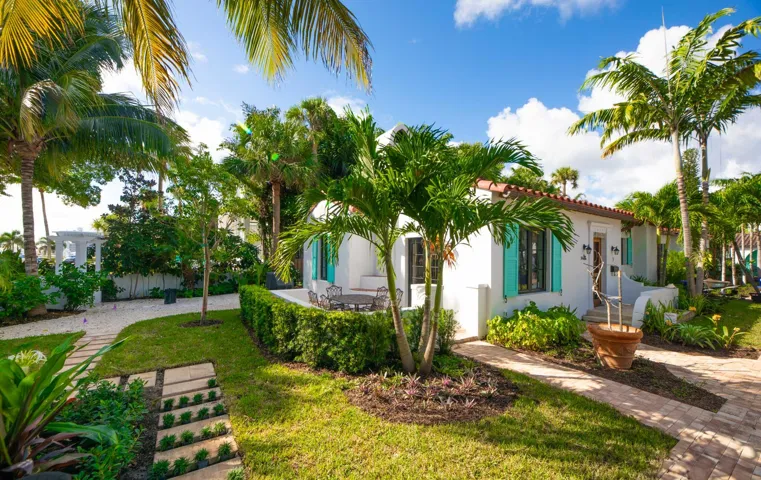 White stucco exterior with a terra cotta tile roof, featuring turquoise louvered shutters