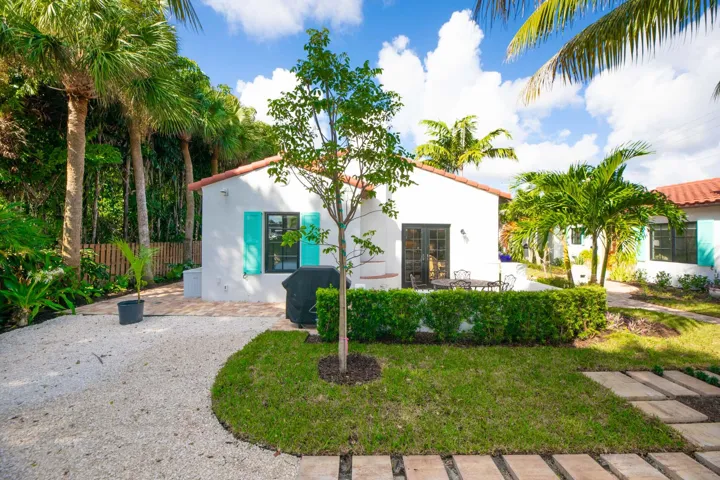White stucco exterior featuring a red tile roof, turquoise louvered shutters, and all impact glass windows and french doors.