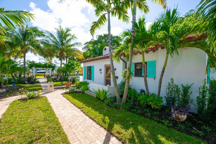 White stucco exterior with a terra cotta tile roof and turquoise shutters