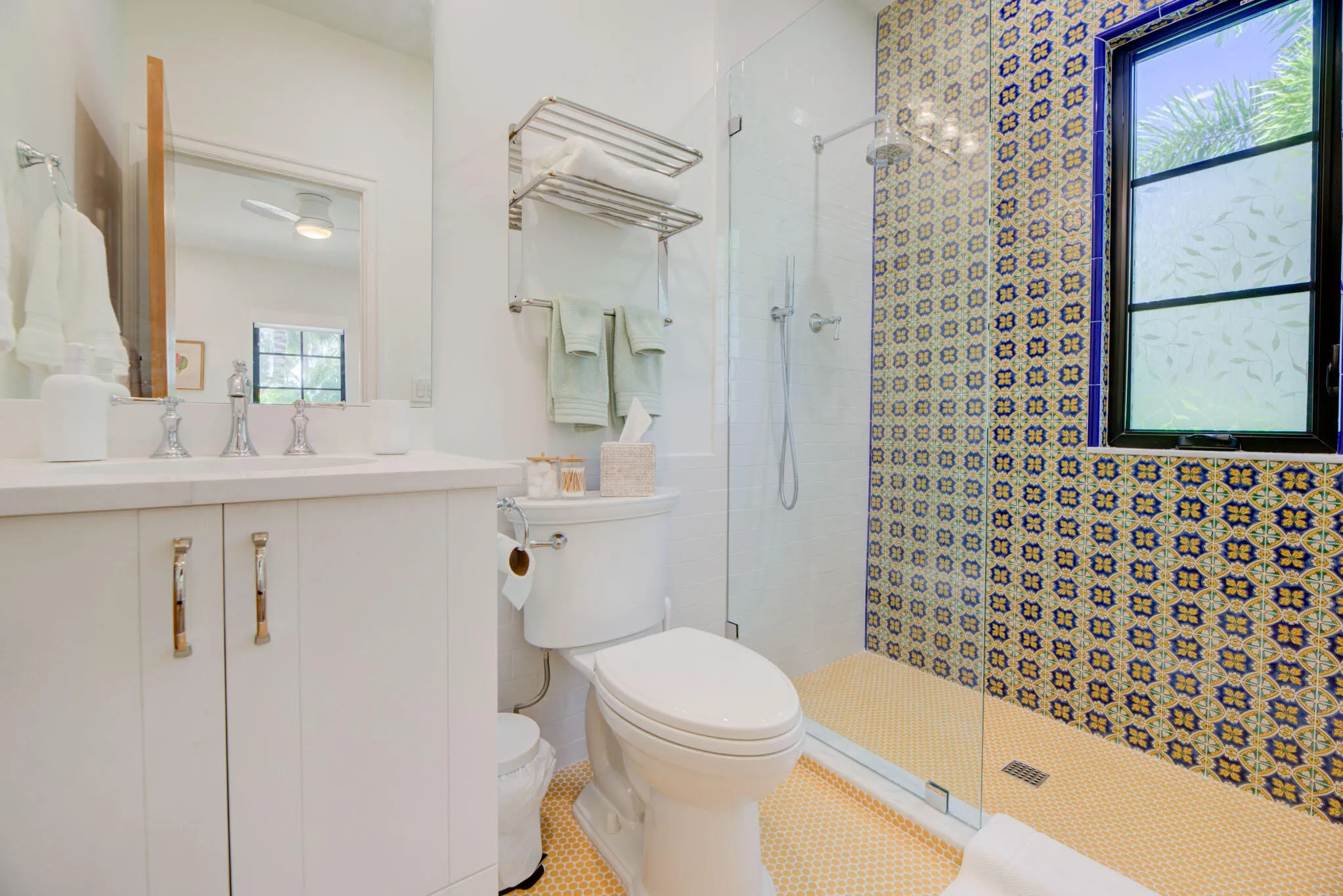 Bathroom featuring patterned wall tiling, a walk-in shower with glass enclosure, a white vanity with integrated sink, and an opaque window with dark trim