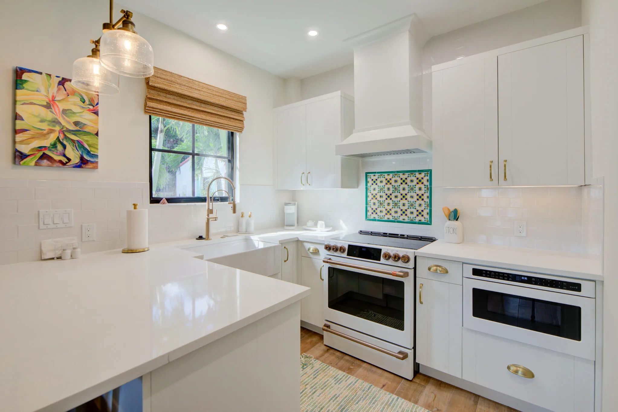 Contemporary kitchen featuring white cabinetry, light-colored countertops, a built-in microwave, and a white range with a coordinating vent hood