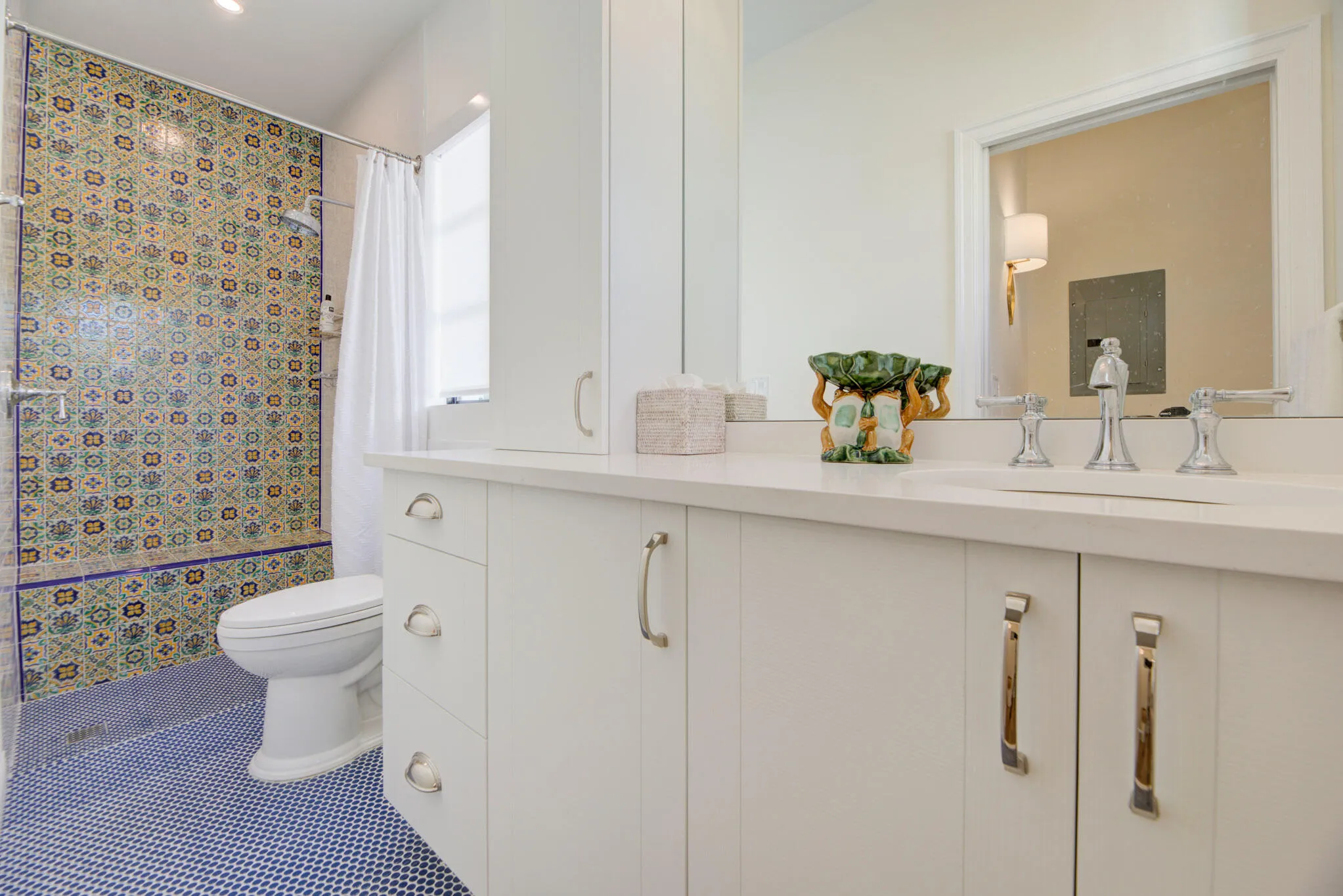 Bathroom featuring a patterned tile shower, blue mosaic floor tiles, a white vanity with integrated sink, chrome fixtures, and recessed lighting