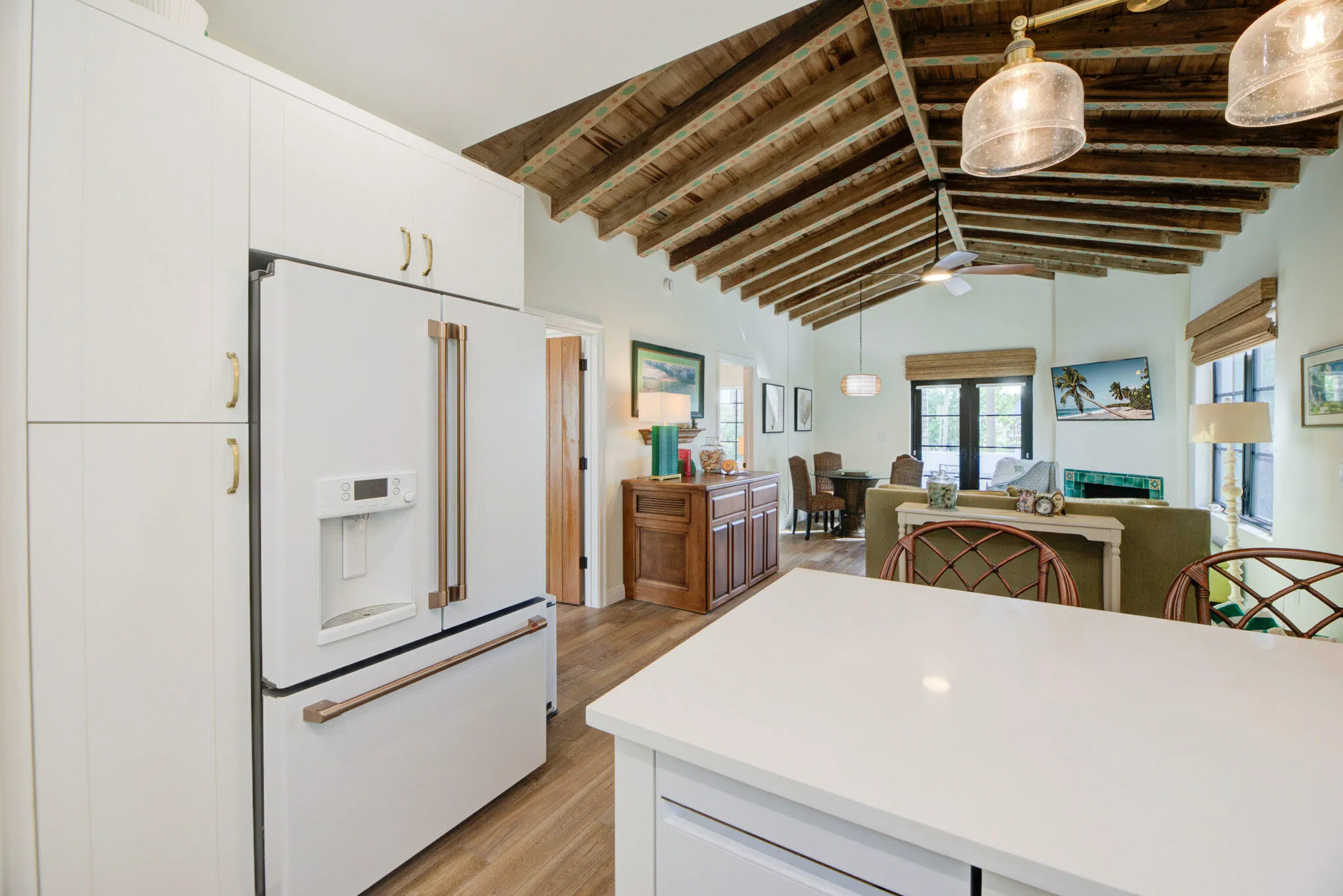 Kitchen featuring a white GE Cafe French door refrigerator with copper-tone hardware, integrated white cabinetry, and a white countertop island