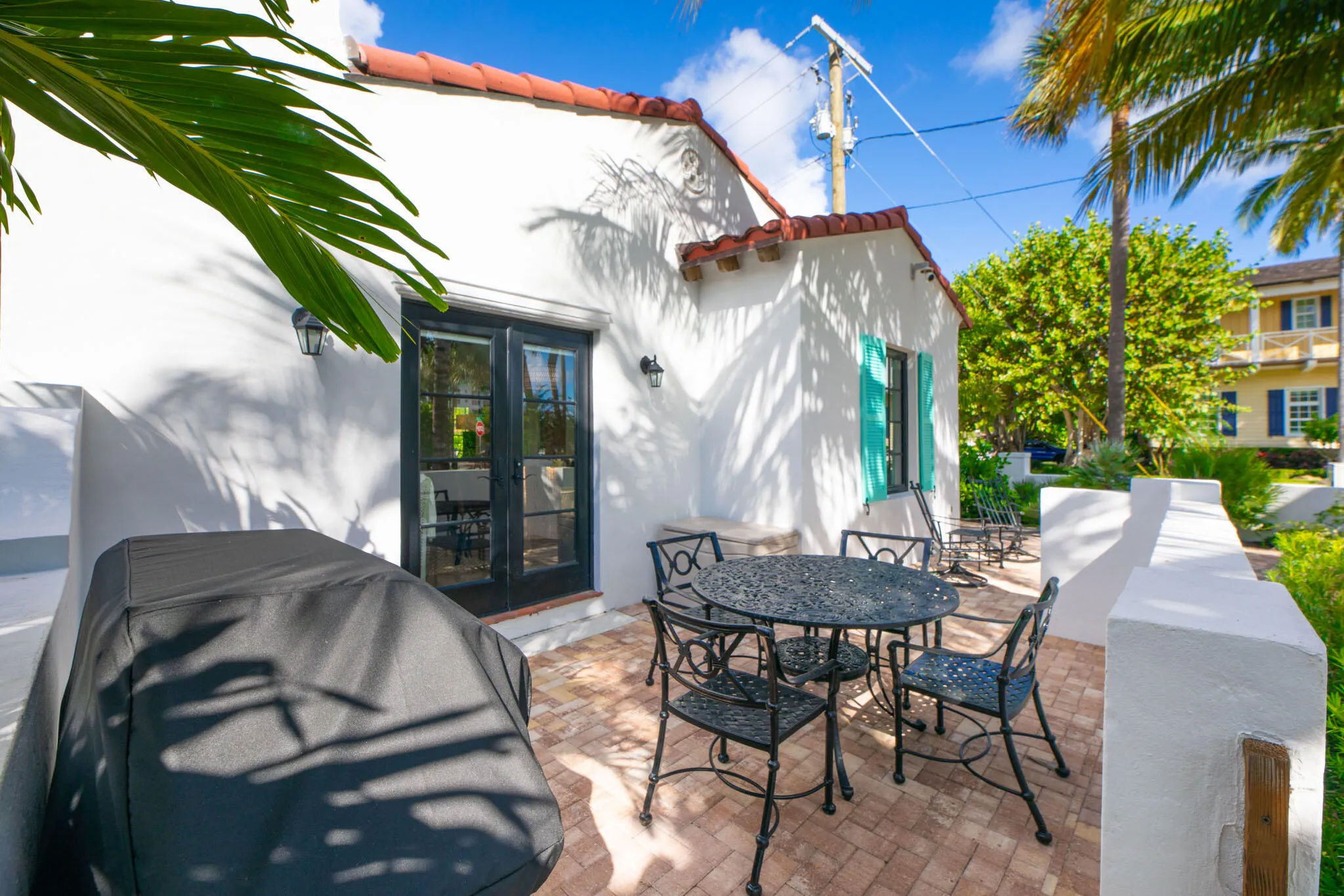Exterior patio with brick-finish flooring, white stucco walls, and a red tile roof