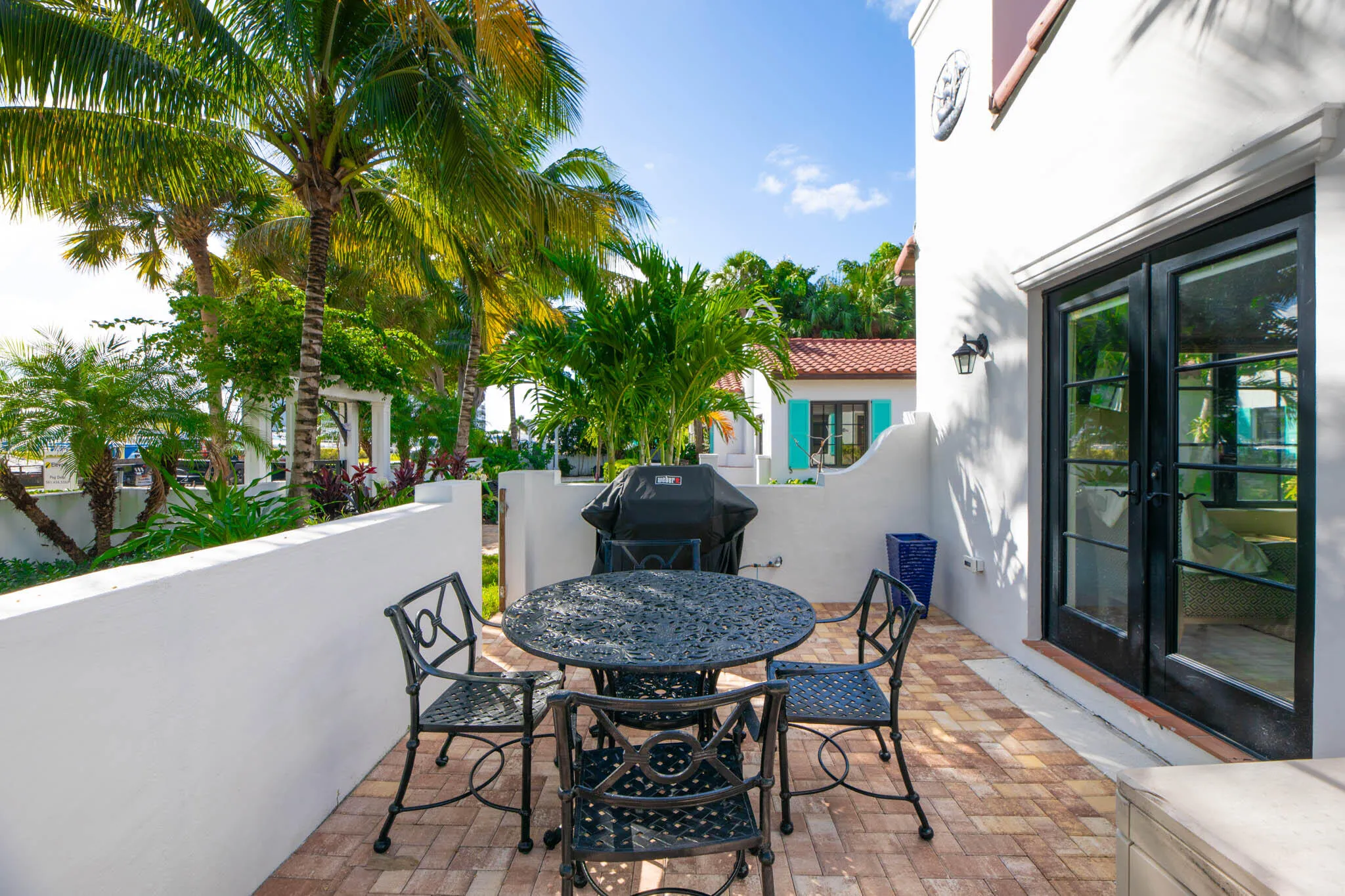 Outdoor patio featuring brick-laid flooring and a white stucco wall, gas grill.