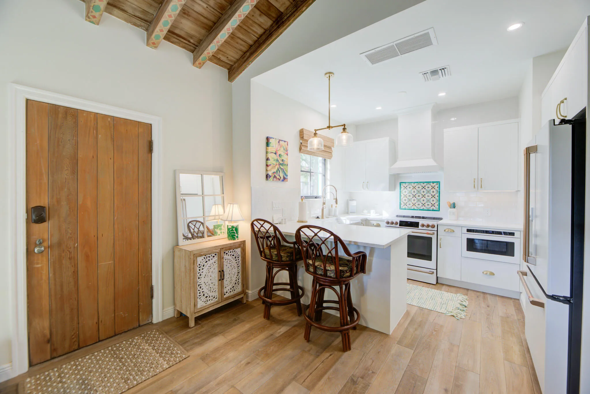 Open-concept kitchen featuring white custom cabinetry, a built-in microwave, and a white range with a decorative tile backsplash
