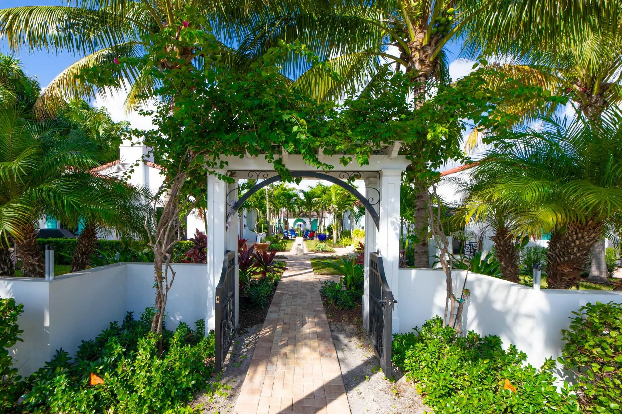 Entryway pergola with climbing greenery, featuring a brick paver pathway into the private community courtyard.