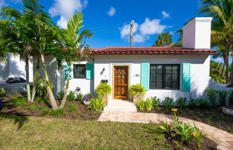 Spanish mediterranean free-standing villa featuring a red tile roof and white chimney, impact glass windows and french doors.