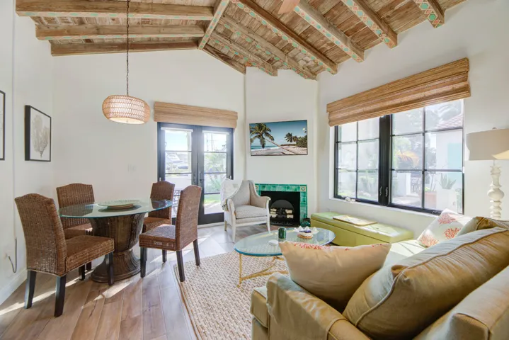 Vaulted wood-beamed ceilings with decorative accents, large picture impact glass windows, wood-finish flooring, and a tiled fireplace surround
