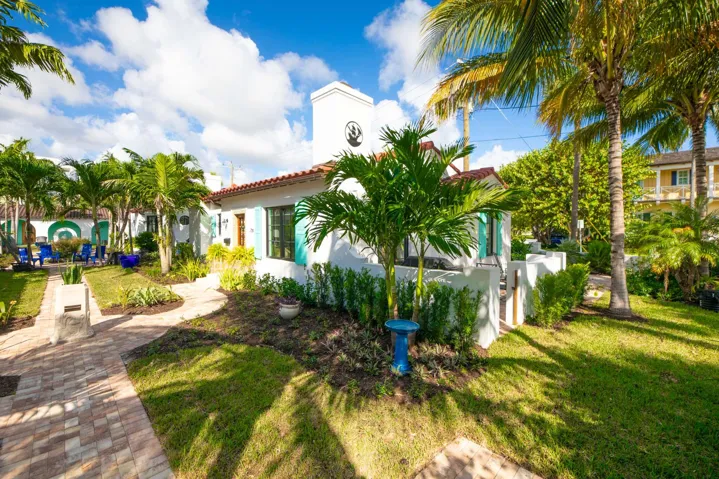 Spanish Colonial style exterior with white stucco, terracotta tile roof, and teal shutters