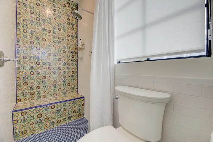 Shower with patterned tile surround, integrated bench seating, and a mosaic tile floor