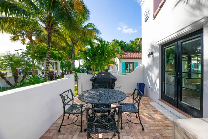 Outdoor patio featuring brick-laid flooring and a white stucco wall, gas grill.