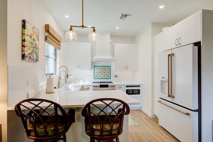 Contemporary kitchen featuring white cabinetry, light-toned wood-finish flooring, and a patterned tile backsplash