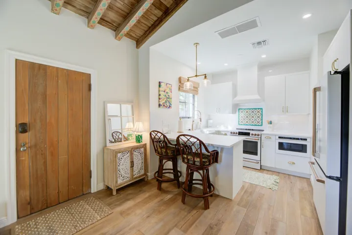 Open-concept kitchen featuring white custom cabinetry, a built-in microwave, and a white range with a decorative tile backsplash