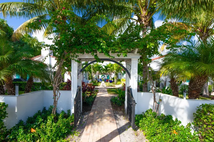 Entryway pergola with climbing greenery, featuring a brick paver pathway into the private community courtyard.