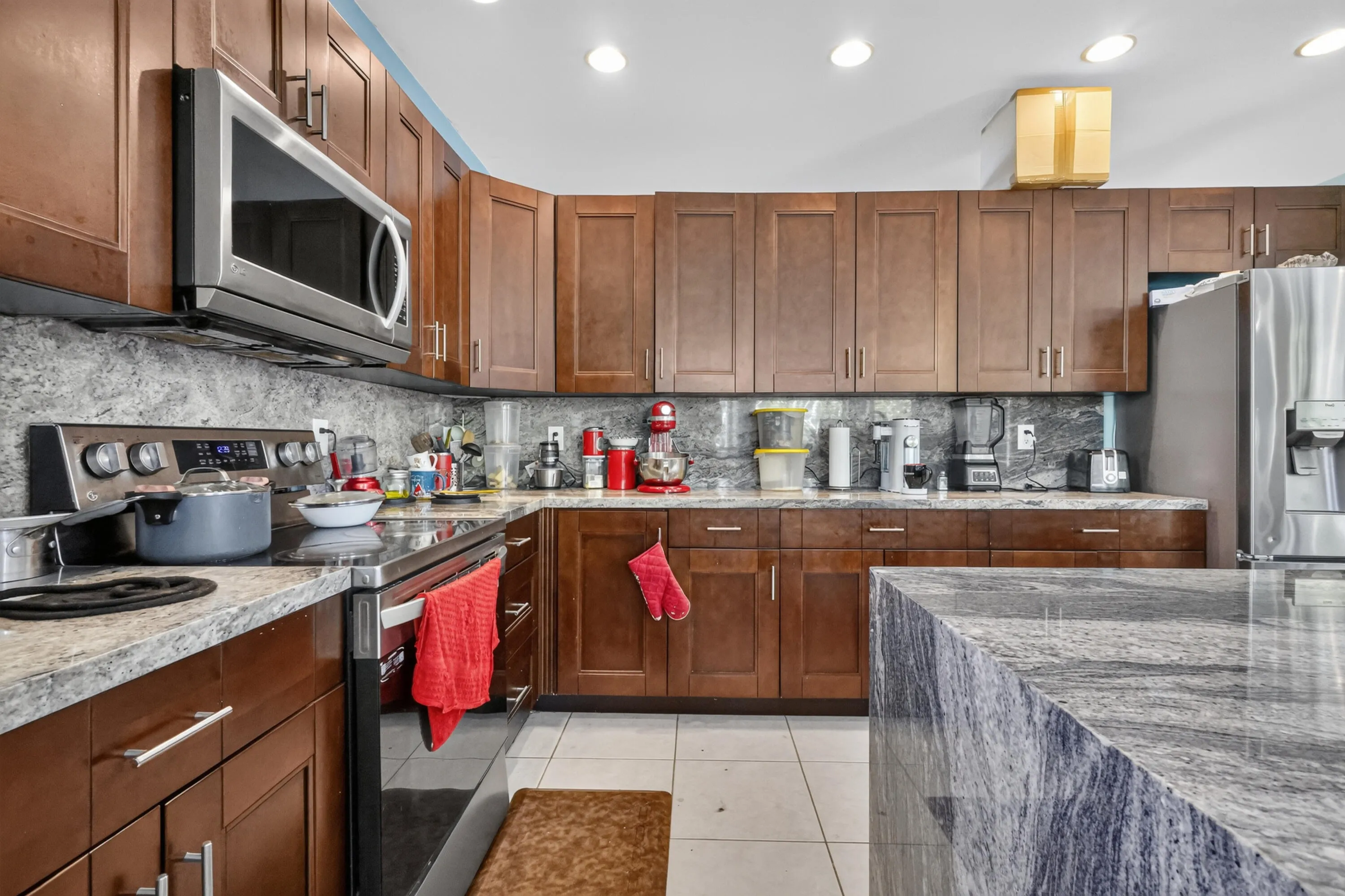 Chef's kitchen featuring rich wood cabinetry, stainless steel appliances, and granite countertops with waterfall island