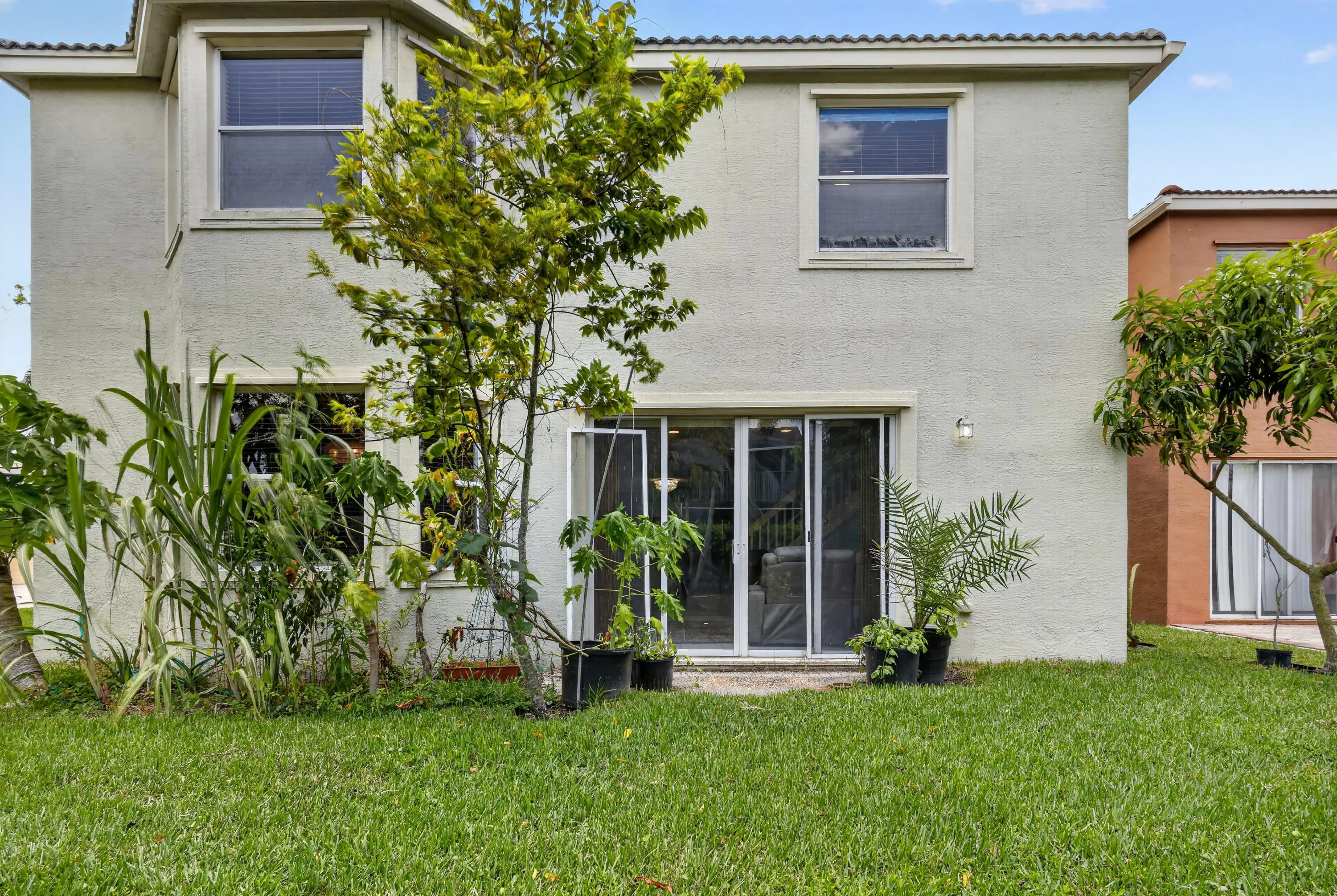 Rear exterior with stucco siding, multiple windows, and a sliding glass door