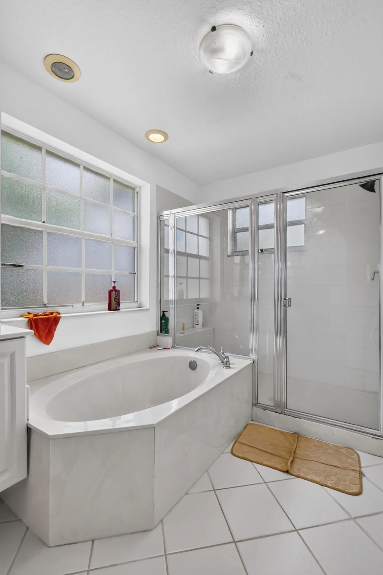 Spacious bathroom featuring a built-in soaking tub, a separate glass-enclosed shower, and large privacy windows